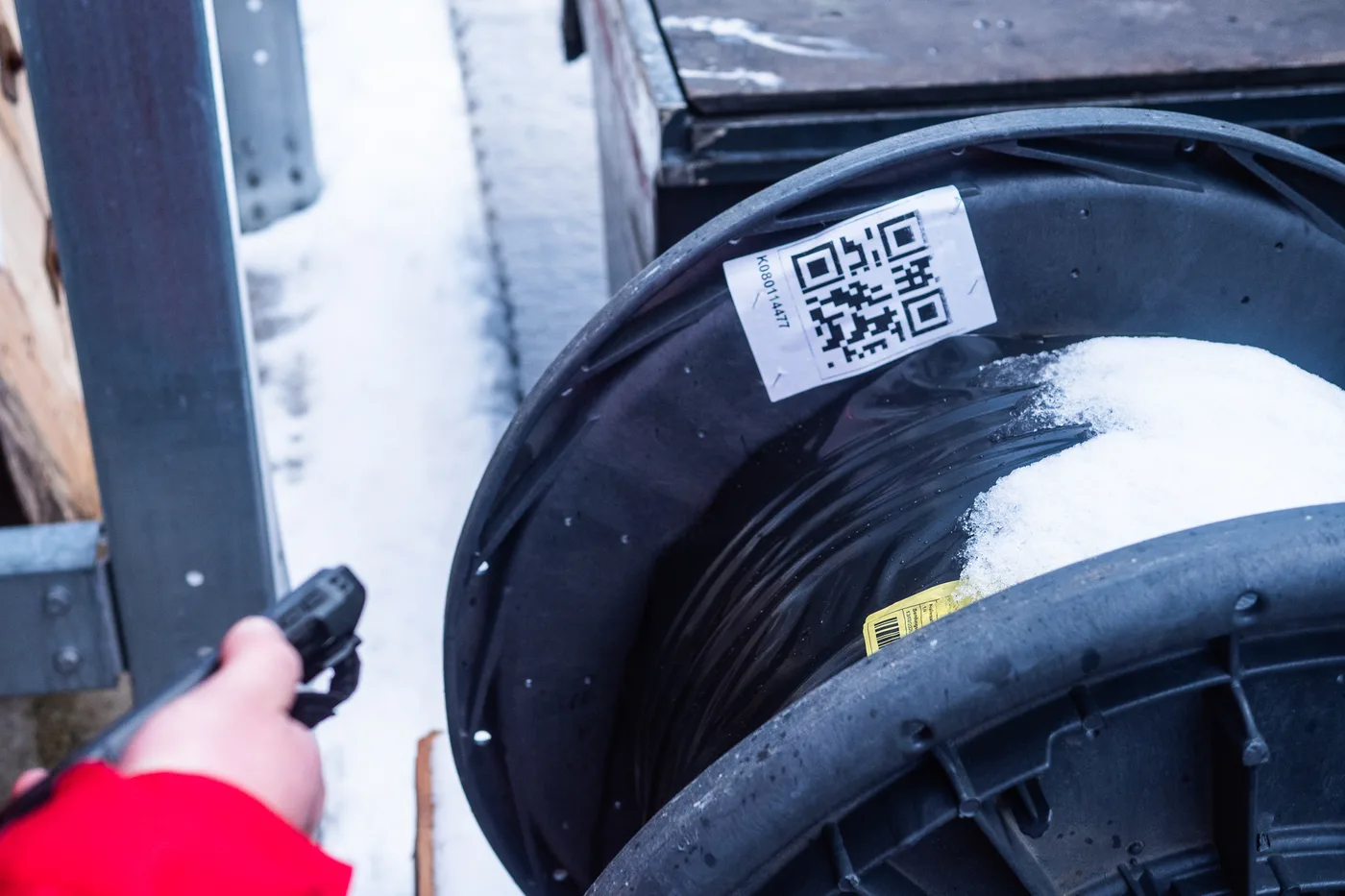 Hand mit Scanner erfasst den QR-Code einer Kunststoff-Kabeltrommel