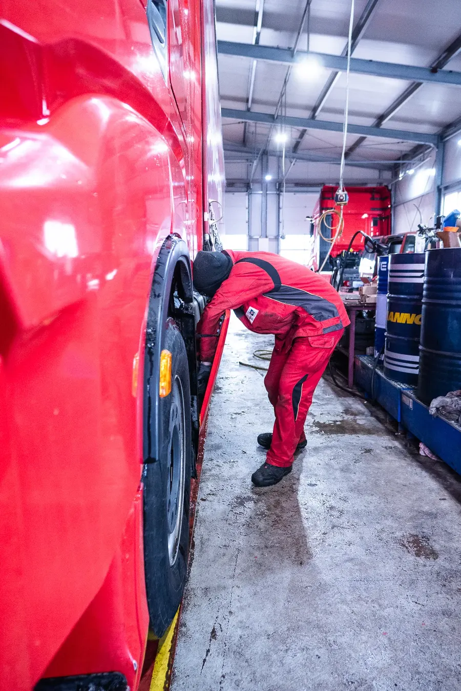 Mechaniker arbeitet am Radkasten eines roten LKW in der Werkstatthalle