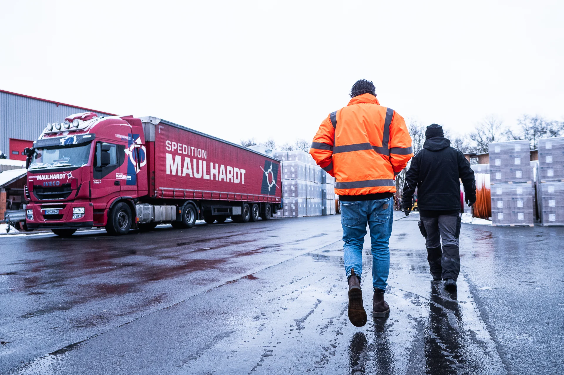 Zwei Kollegen gehen gemeinsam über den Hof zu einem Sattelzug der Spedition Maulhardt