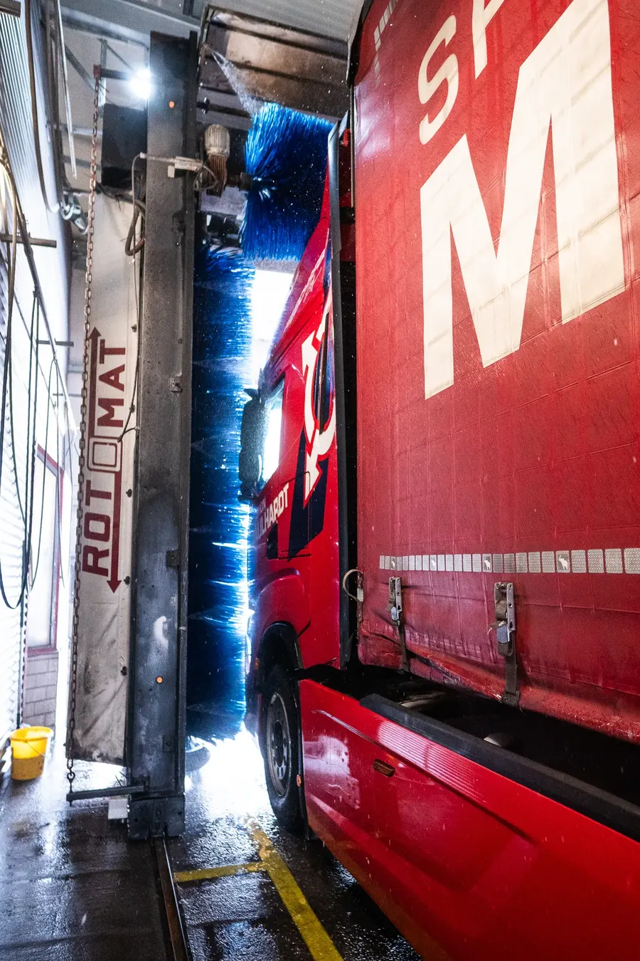 Sattelzug fährt durch das Waschportal, die blaue Bürste reinigt das Fahrerhaus