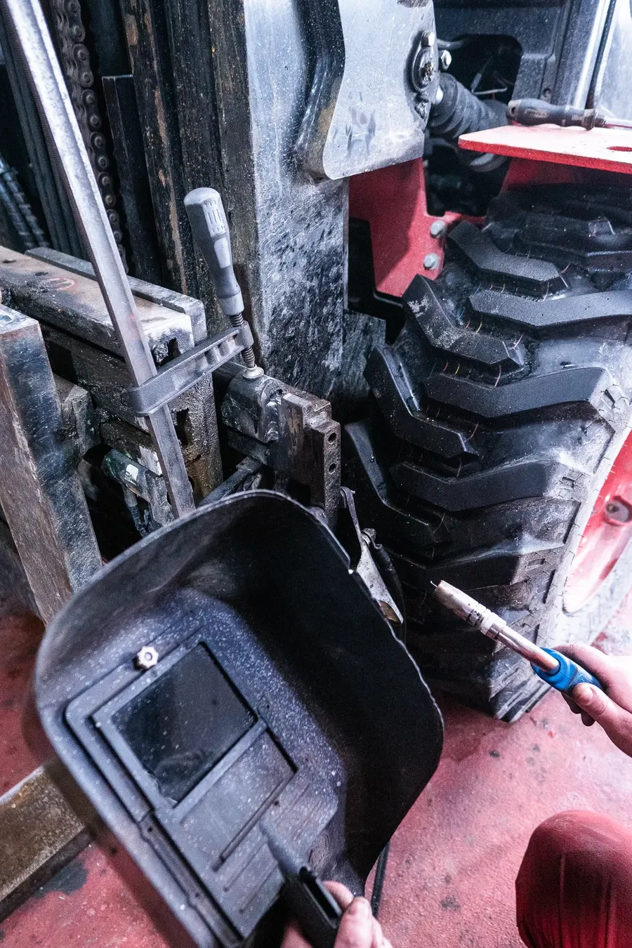 Schweißarbeiten am Staplermast in der Werkstatt, Hand mit Schweißschirm und Brenner